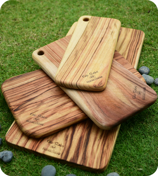 A group of four wooden cutting boards on top of grass.