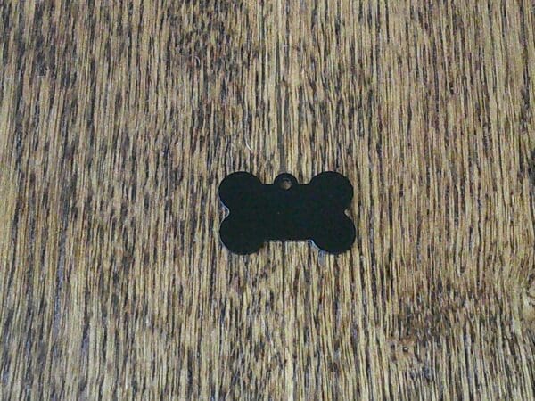 A wooden table with a black bone shaped tag on it.