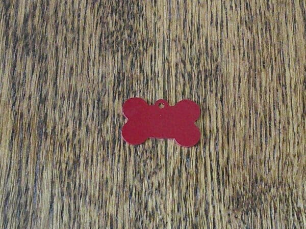 A red bone shaped tag on a wooden surface.