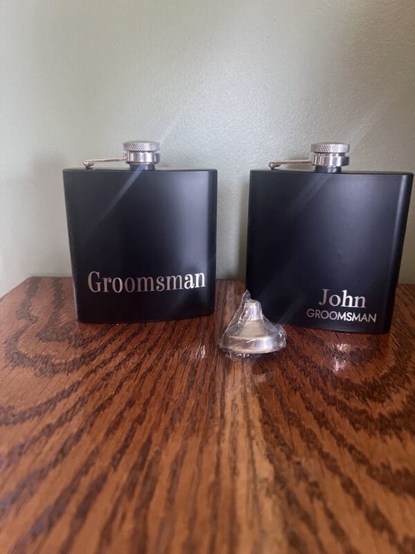 Two black flasks sitting on top of a wooden table.