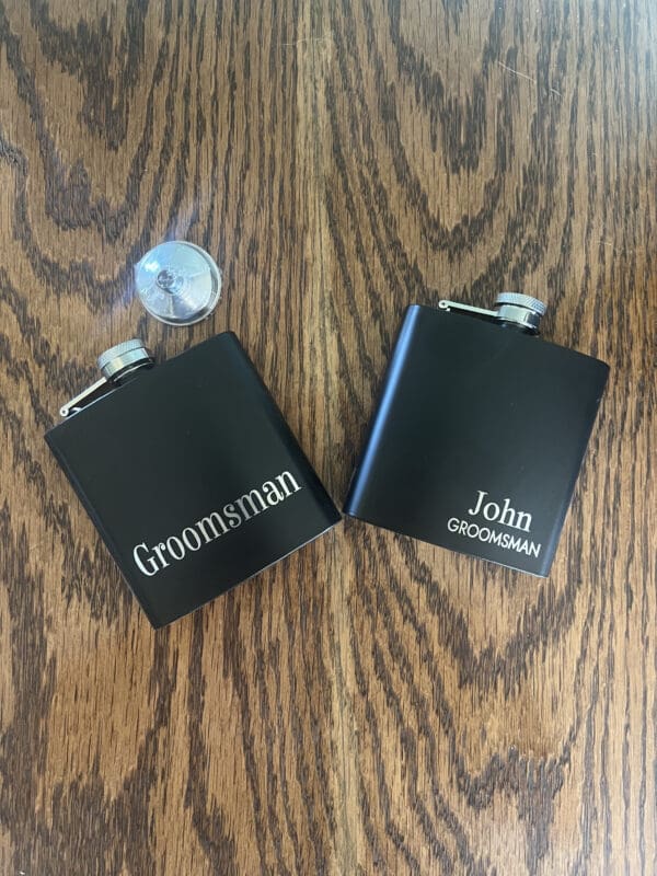 Two black flasks sitting on top of a wooden table.