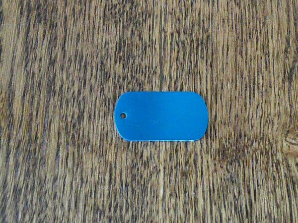 A blue dog tag sitting on top of a wooden floor.