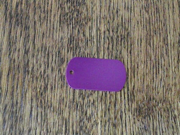 A purple dog tag sitting on top of a wooden table.