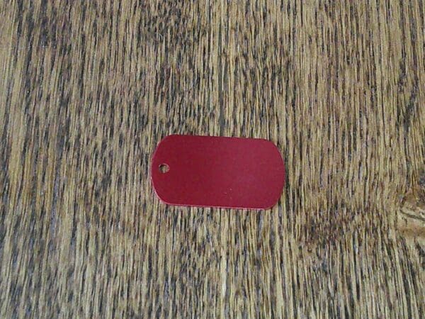 A red dog tag sitting on top of a wooden floor.